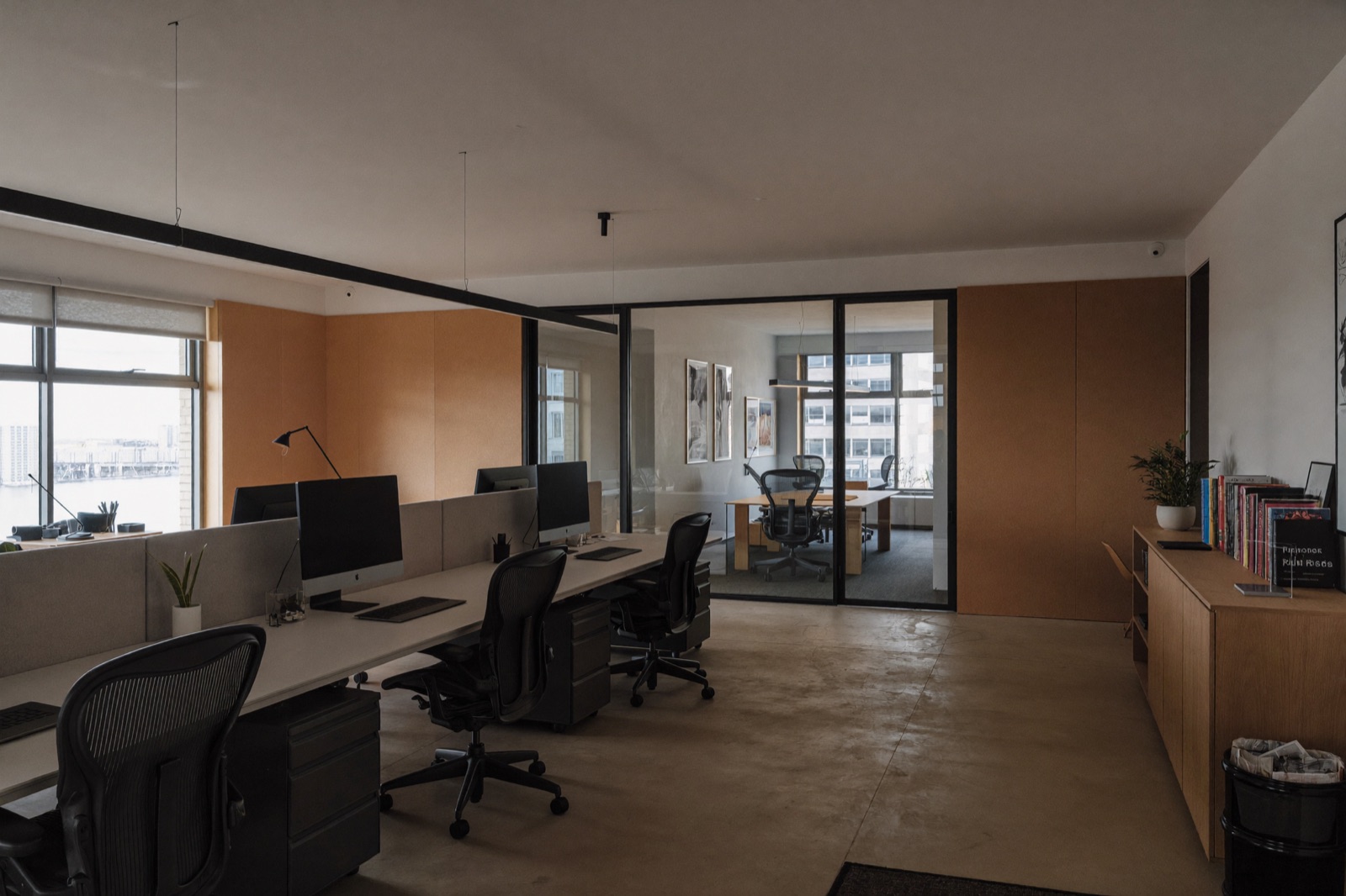 Współczesne wnętrze biurowe ze współdzielonymi biurkami, ergonomicznymi fotelami i przeszkloną salą spotkań w tle
